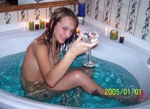 Nudo ragazza a bere il vino in un bagno